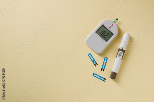 Top view of glucometer, lancet pen and strips on yellow background. diabetes test kit