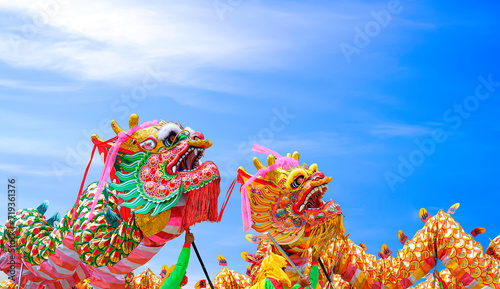 Two colorful Chinese dragon dance performances against blue sky background during Chinese New Year celebrate festival