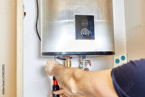 the man tightens the pipe nut in the water heating system. The master installs the water heater. The concept of bathroom maintenance.