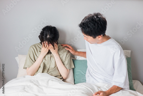 ベッドで悲しむ妻を慰める夫 