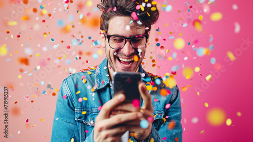 Happy young man using his smart phone with confetti