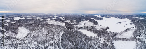 Aerial view over taiga landscape with snow covered boreal forest and frozen lakes in northeast Finland