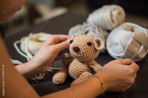 Close up view of hands crocheting a toy teddy bear. 