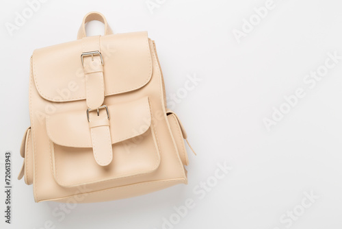 Beige stylish backpack on color background, top view.