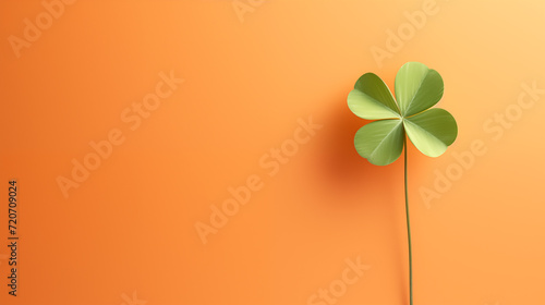 Imagen minimalista de un trébol de cuatro hojas sobre un fondo de color naranja claro con espacio para meter texto