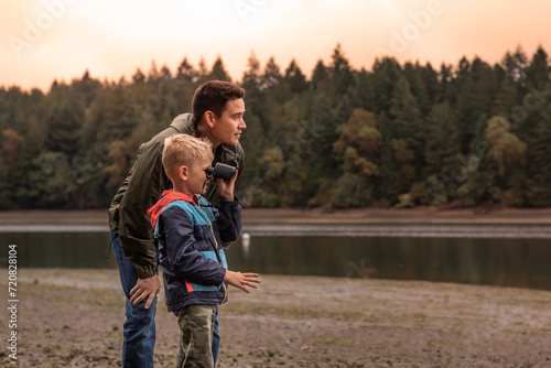 Father and son outdoors family adventure discovering nature together looking at wildlife with binoculars 