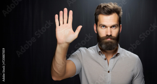 Man with beard and mustache making stop gesture with his hand on black background