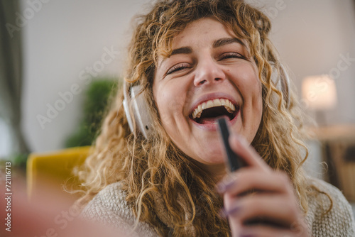 One woman with headphones at home listen music online happy smile sing