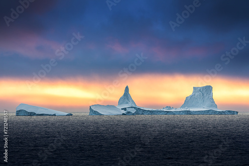 Iceberg swimming in the polar sea in front of midnight sun in Antarctica