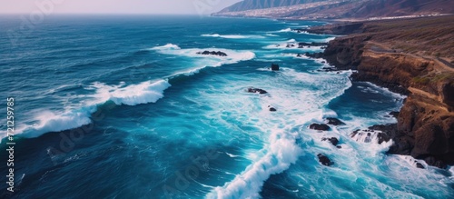 Tenerife's volcanic coast experiences dramatic waves in aerial view.