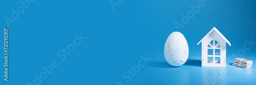 Easter egg and house on blue background, buy and sell property, springtime discount, festive credit