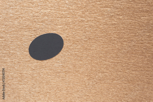 black paper oval on metallic gold crepe paper