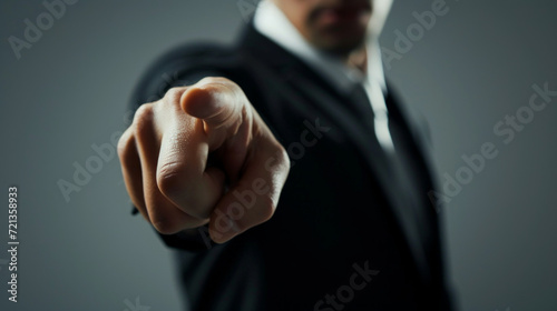  A businessman wearing a suit pointing at the camera. Shallow depth of field. Angry man, accusatory. Blame.