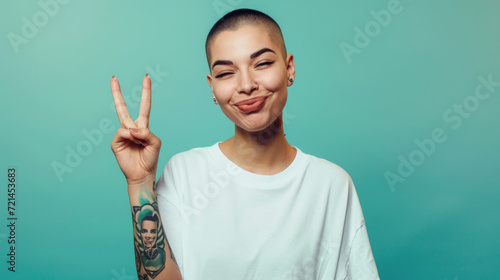 confident young woman with a buzz cut, winking and making a peace sign with her fingers, set against a teal background.