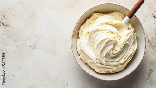 A bowl of rich, white creamy frosting with a wooden spoon