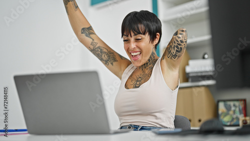 Hispanic woman with amputee arm business worker using laptop working with winner gesture at the office