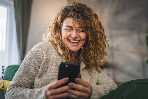 One woman with curly hair at home use mobile phone smartphone sms texting or browse internet