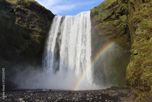 Iceland waterfall green grass and rainbow