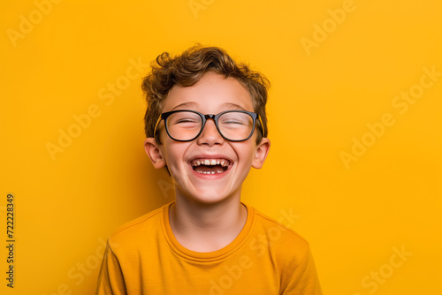 Menino sorrindo feliz de óculos com camiseta amarela isolado no fundo amarelo