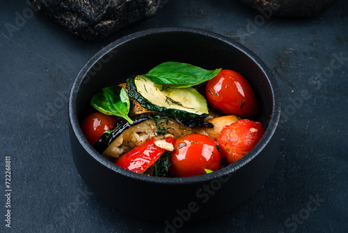 Garnish pickled vegetables zucchini, eggplant, tomatoes with spices and herbs on a dark background.