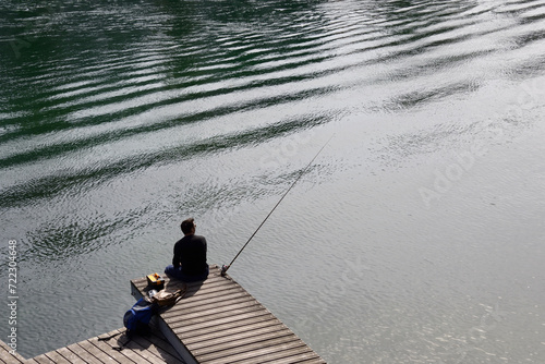 Geneva, Switzerland, Europe - single man rod fishing from Rhone river, leisure on river shore, peaceful spring day