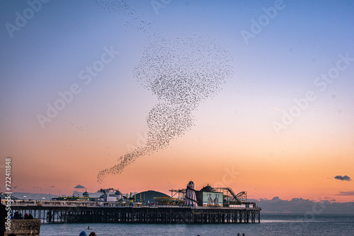 Murmuration around Brighton pier winter time as Starling bird return, East Sussex, UK