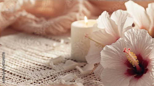  a couple of white flowers sitting on top of a table next to a white candle and a lace doily.