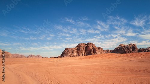 Wadi Rum, Jordan, Scenic view of Arabic Middle Eastern desert against clear blue sky with sand tracks in foreground. Mountain in background. Copy space no people