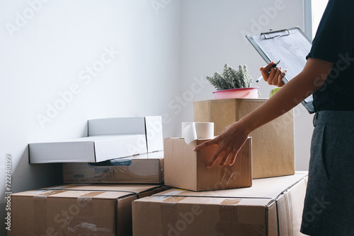 Woman checking and packing the carton box prepare to move to new house relocation shipping 