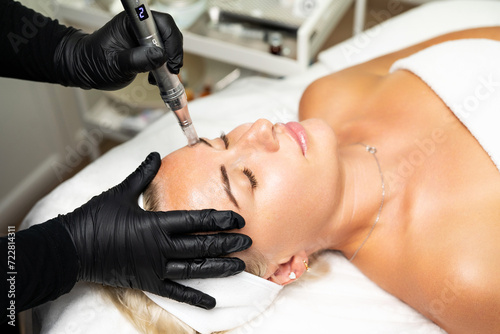 Microneedle RF lifting procedure. A cosmetologist performs a facial rejuvenation procedure on a woman. Hardware cosmetology.