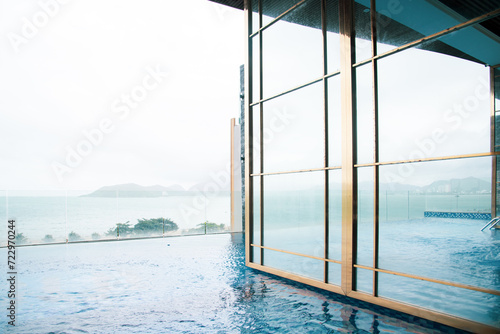Glass wall of Infinity pool with ocean and mountain range view at luxury resort hotel in Nha Trang, Vietnam, upscale healthy lifestyle, Asia travel destination, relaxation and recreation