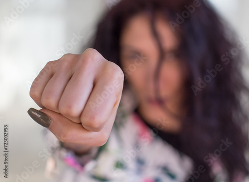Mujer joven lanzando el puño cerrado a cámara con la cara desenfocada