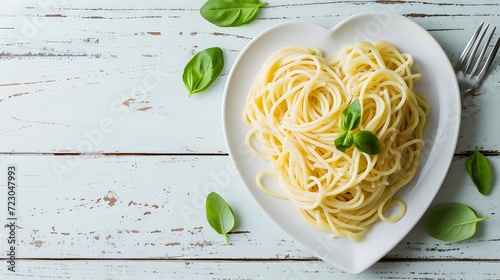 Pasta in heart shaped plate on white wooden table with copy space. cooked spaghetti with spinach
