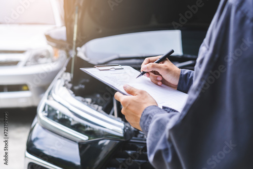 Auto check, car service shop concept. Automobile repairman writing job checklist on clipboard, mechanic checking engine to estimate repair machine, inspecting maintenance by engineer at vehicle garage