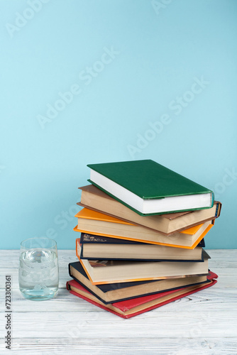 Book stacking. Open book, hardback books on wooden table and green background. Back to school. Copy space for text.