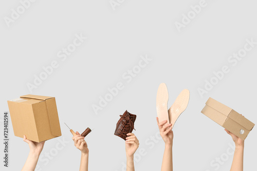 Female hands with boxes, insoles and craft tools on white background. Shoes repair concept