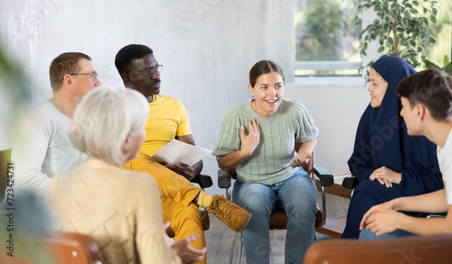 Young female teacher giving lecture to group of multinational students in classroom