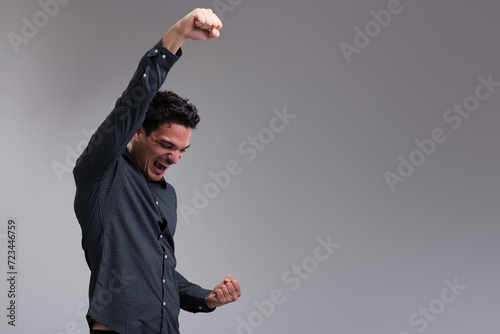 Young man celebrates, arms up, masculine