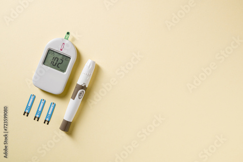 Top view of glucometer, lancet pen and strips on yellow background. diabetes test kit