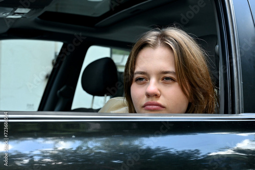 Young woman funny spying and taking photo of someone from car window. Close up