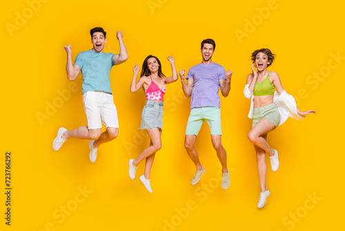 Full body photo of cheerful people buddies jump with raised fists winning isolated over bright color background