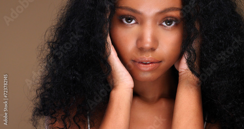 Portrait of a black girl with curly hair, soft makeup and perfect skin. Beautiful face of young black woman with natural skin.