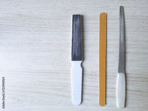 Different types of nail files, manicure tools on a wooden table, top view.