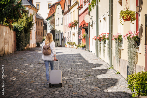 Solo travel. Woman tourist with suitcase and backpack walking on street. Traveling and vacation in european city Olomouc, Czech Republic