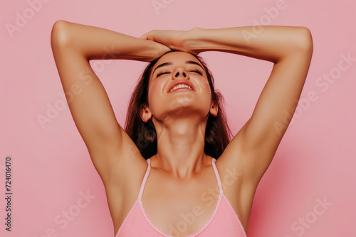 woman put her hands behind her head in against light pink studio background