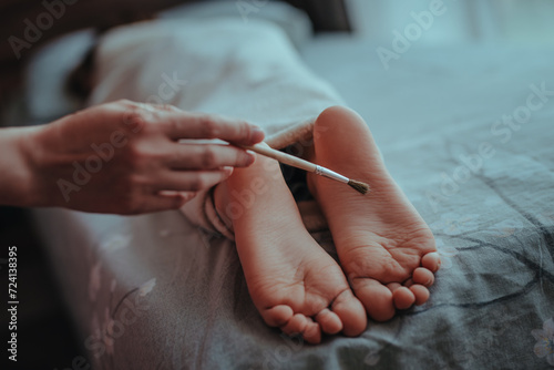 Woman's hand brushes feet of sleeping baby
