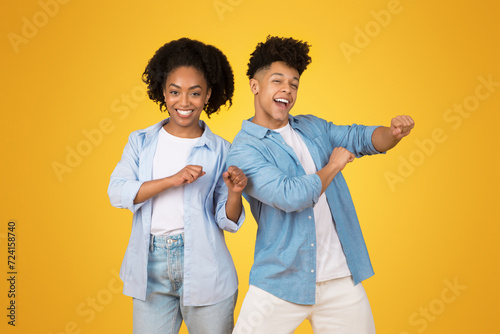 Two joyful African American teenagers dancing, with the young woman in a light blue shirt