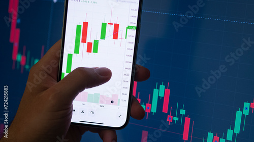 Crypto trader investor broker holding finger using cell phone app executing financial stock trade market at the night. Dark theme, close up shot.