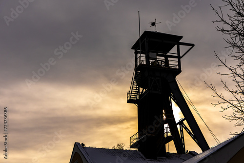 A mine hoist shaft against a dramatic sky background. Close up of the wheels at the top of the shaft.