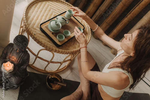 Young woman is pouring hot tea a tea ceremony. Woman hands holding cups. Wooden table with traditional Chinese tea ceremony accessories and cups of tea. Soft focus, blurred and noise effect